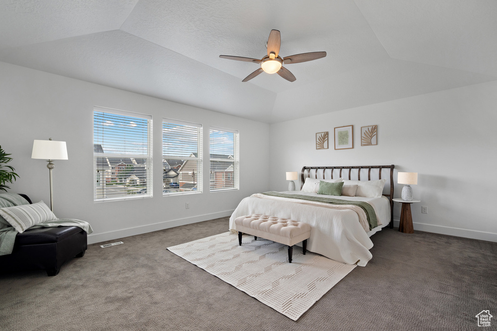 Carpeted bedroom with lofted ceiling, baseboards, and ceiling fan