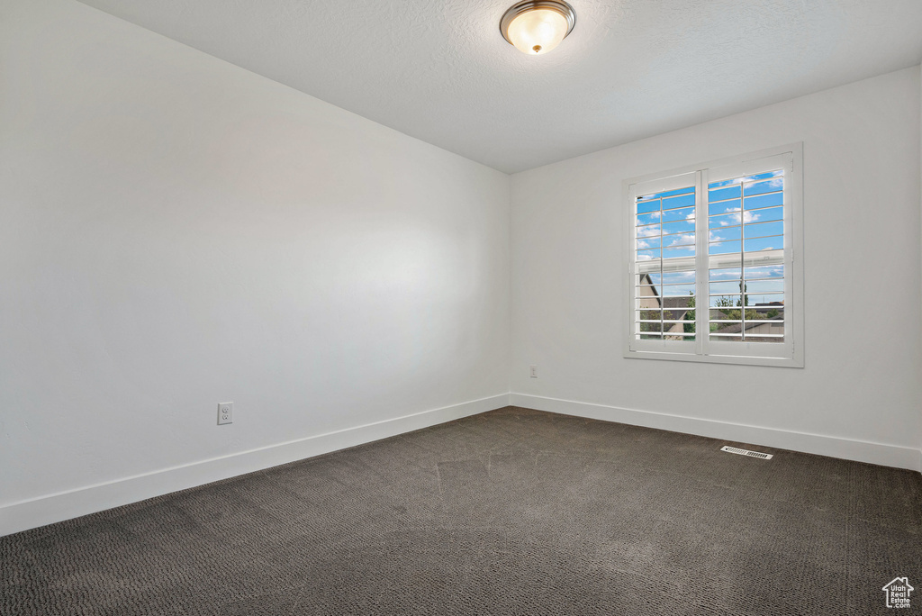 Unfurnished room with baseboards and dark carpet
