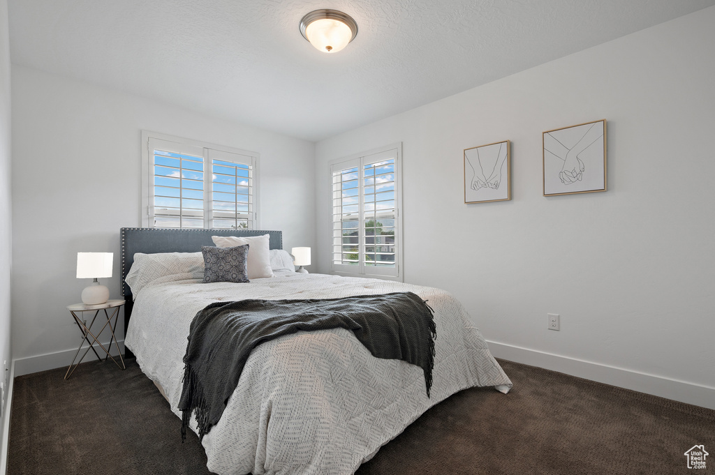 Bedroom with dark carpet and baseboards