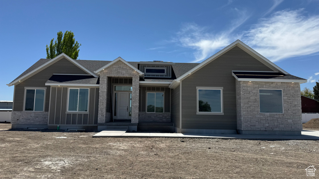 View of front of property with stone siding and roof with shingles