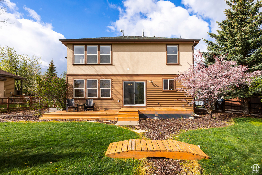 Back of property featuring a wooden deck and stucco siding