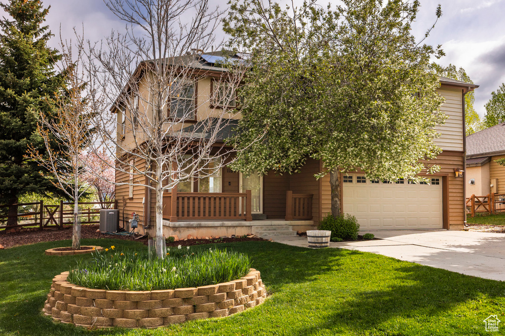 View of front of property featuring concrete driveway, a garage, and cooling unit