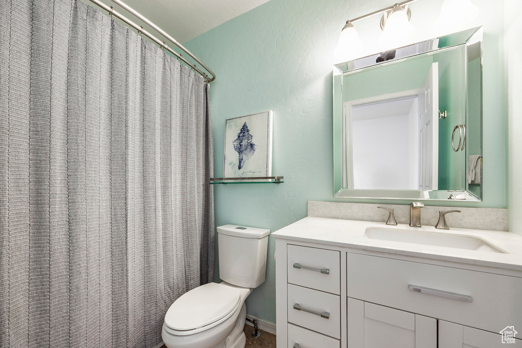 Full bathroom with toilet, vanity, and a shower with curtain