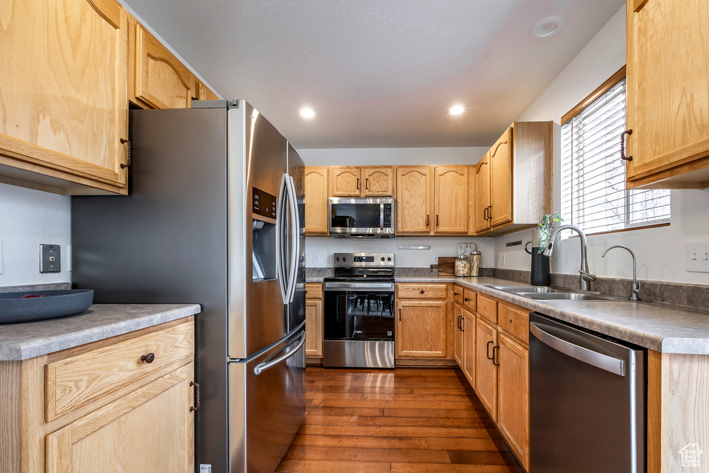 Kitchen with appliances with stainless steel finishes, dark wood-type flooring, a sink, light brown cabinetry, and recessed lighting
