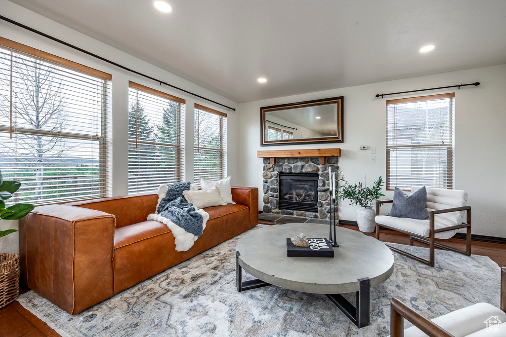 Living room featuring healthy amount of natural light, a stone fireplace, wood finished floors, and recessed lighting