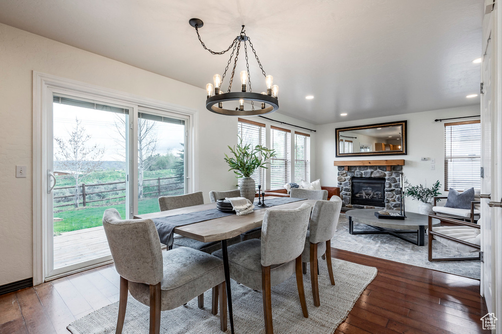 Dining space with plenty of natural light, a chandelier, dark wood-style flooring, a fireplace, and recessed lighting