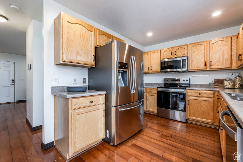 Kitchen featuring stainless steel appliances, dark wood-style floors, light brown cabinets, recessed lighting, and a sink