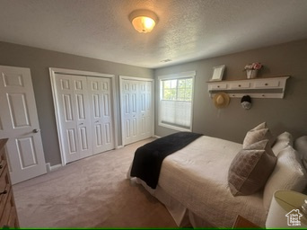 Carpeted bedroom featuring multiple closets, a textured ceiling, and baseboards