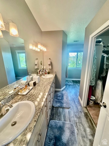Bathroom with plenty of natural light, wood finished floors, double vanity, and baseboards