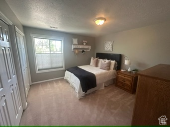 Bedroom featuring a textured ceiling, light carpet, and baseboards