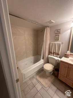 Full bathroom with tile patterned floors, toilet, vanity, and a textured ceiling
