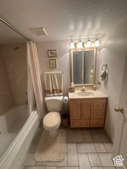 Full bathroom featuring toilet, vanity, shower / bath combo with shower curtain, and tile patterned flooring