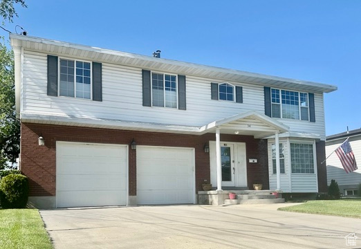 View of front of home featuring an attached garage, concrete driveway, and brick siding
