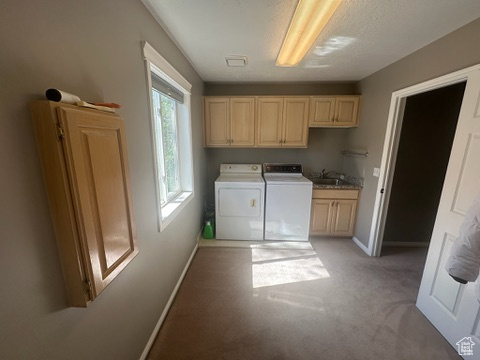 Washroom with independent washer and dryer, cabinet space, baseboards, and light colored carpet