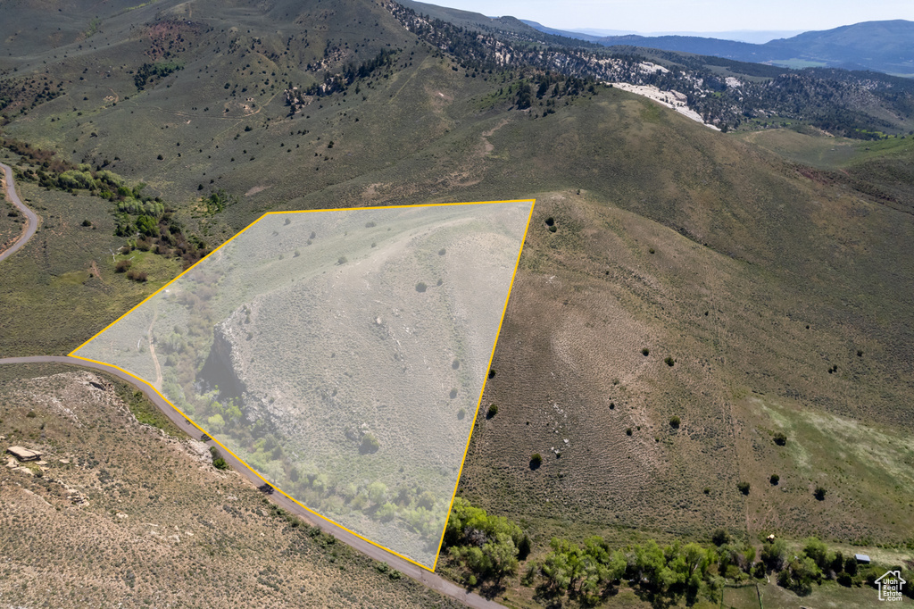 Aerial view of sparsely populated area featuring a mountainous background and property parcel outlined