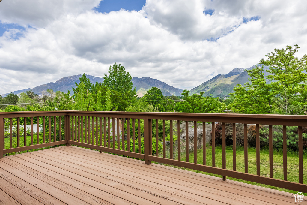 Wooden deck featuring a mountain view and a yard