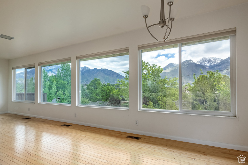 Unfurnished room with baseboards, hardwood / wood-style floors, a chandelier, and a mountain view