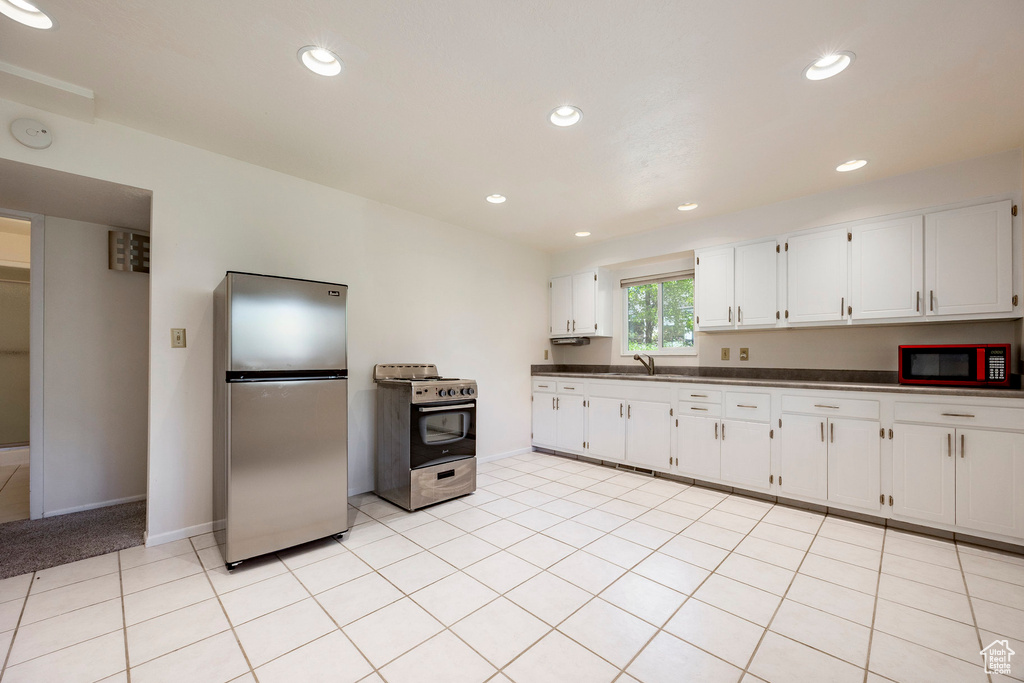 Kitchen featuring stainless steel appliances, dark countertops, white cabinetry, baseboards, and recessed lighting
