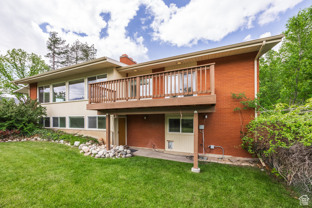 Back of property with a lawn, brick siding, and a wooden deck