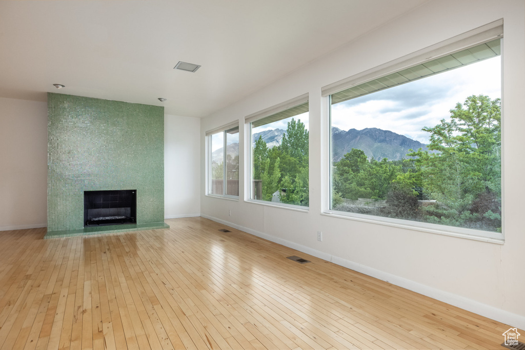 Unfurnished living room with wood-type flooring, a large fireplace, and baseboards