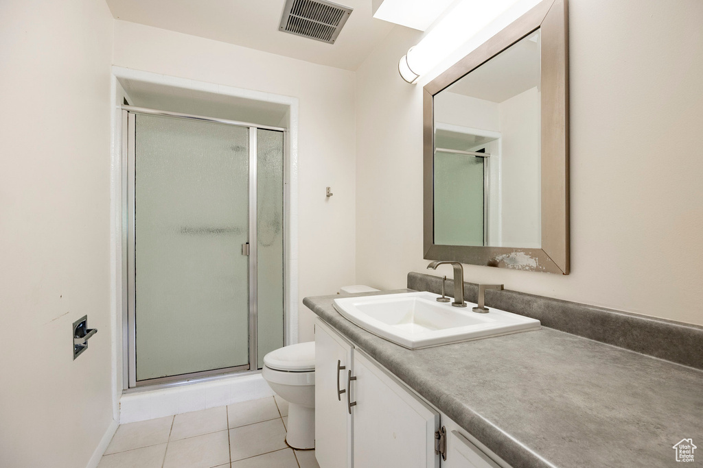 Full bathroom featuring toilet, vanity, a stall shower, and tile patterned flooring
