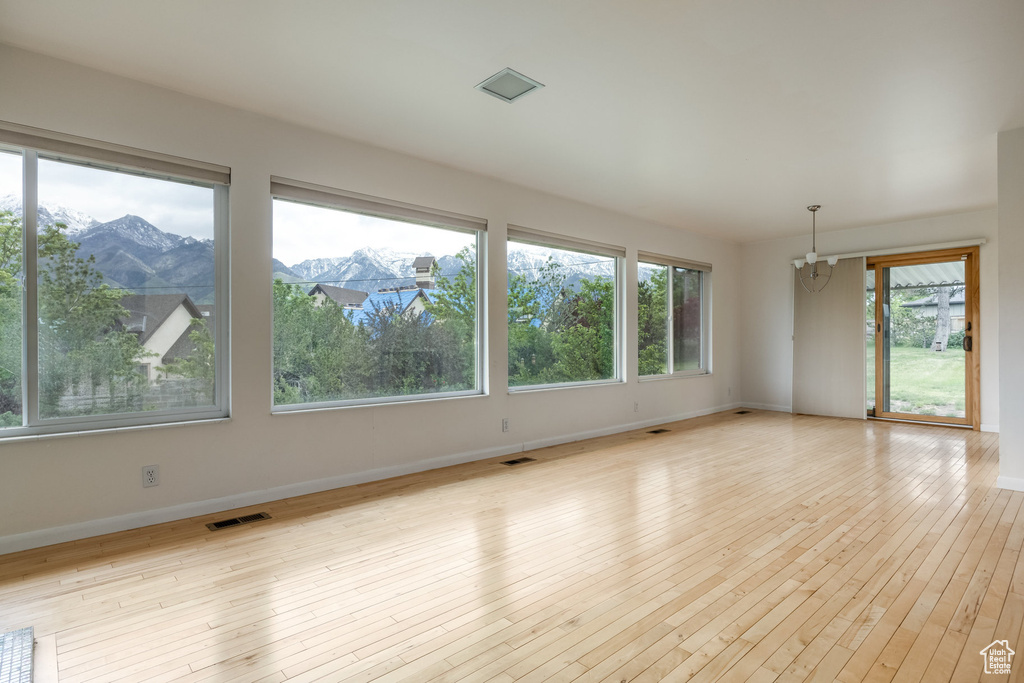 Empty room featuring baseboards, light wood-style flooring, and a mountain view
