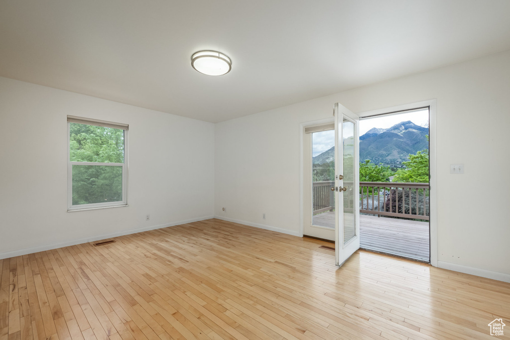 Unfurnished room with french doors, light wood-style flooring, a mountain view, and baseboards
