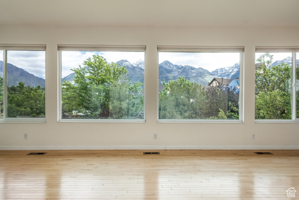 Spare room featuring a mountain view, hardwood / wood-style flooring, and plenty of natural light