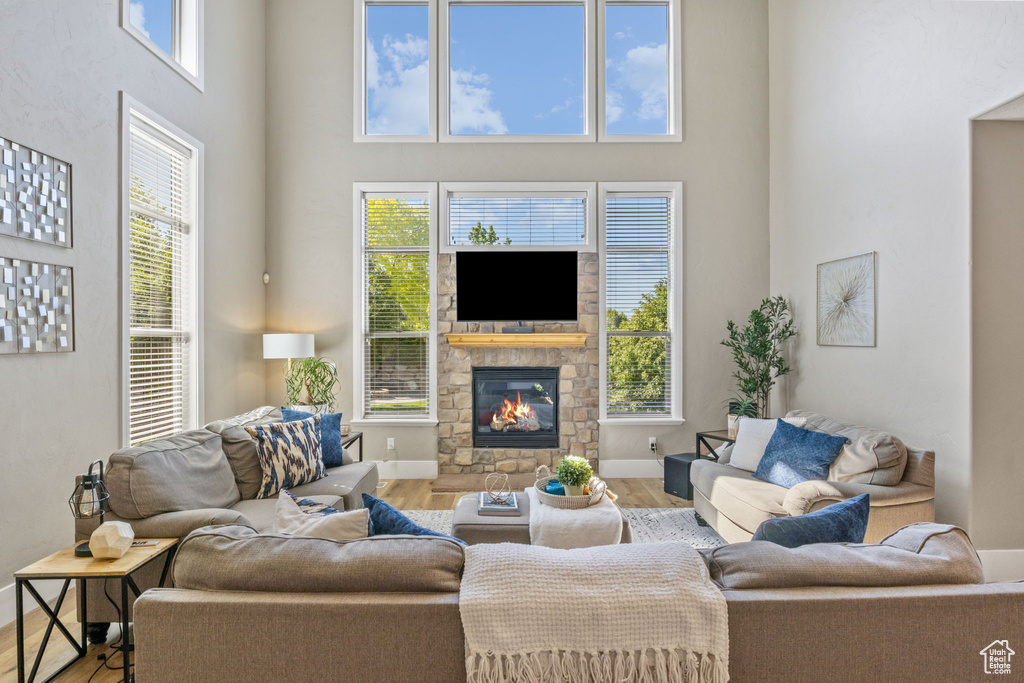 Living room with a towering ceiling, wood finished floors, a stone fireplace, and baseboards