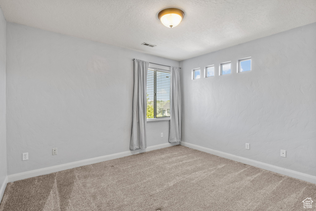 Unfurnished room with a textured ceiling, carpet flooring, and baseboards