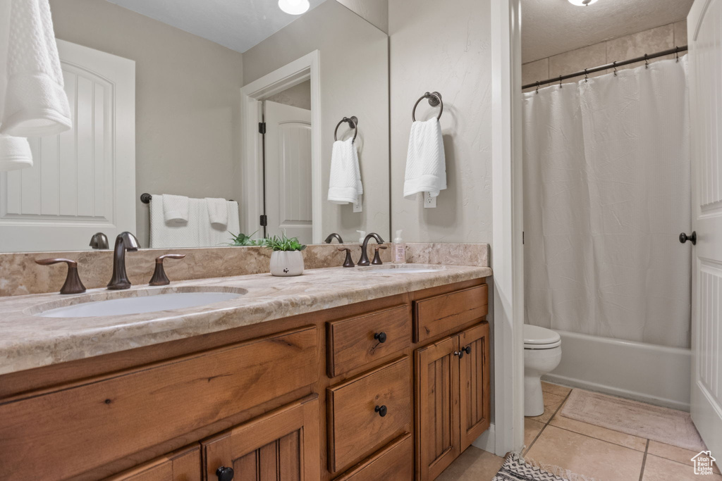 Full bath featuring double vanity, toilet, tile patterned floors, and shower / bath combination with curtain