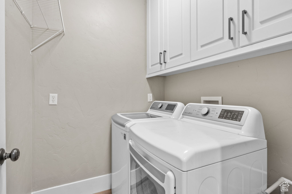 Washroom with washing machine and clothes dryer, cabinet space, and baseboards