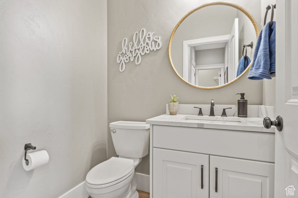 Half bath featuring toilet, vanity, and baseboards