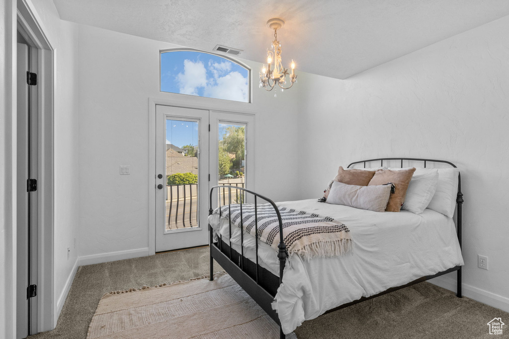 Carpeted bedroom featuring access to outside, a chandelier, and baseboards