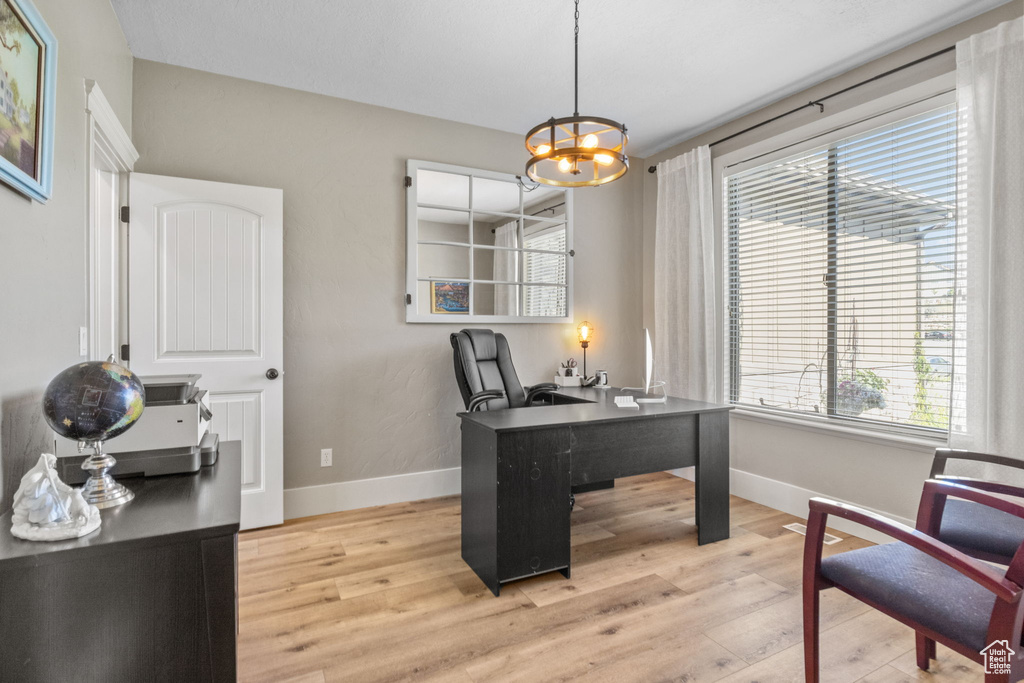 Home office featuring baseboards, light wood-style floors, and a chandelier