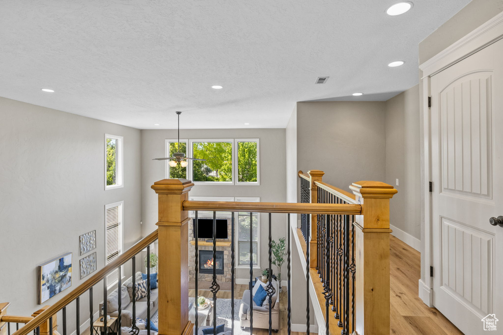 Hallway with an upstairs landing, recessed lighting, wood finished floors, and baseboards