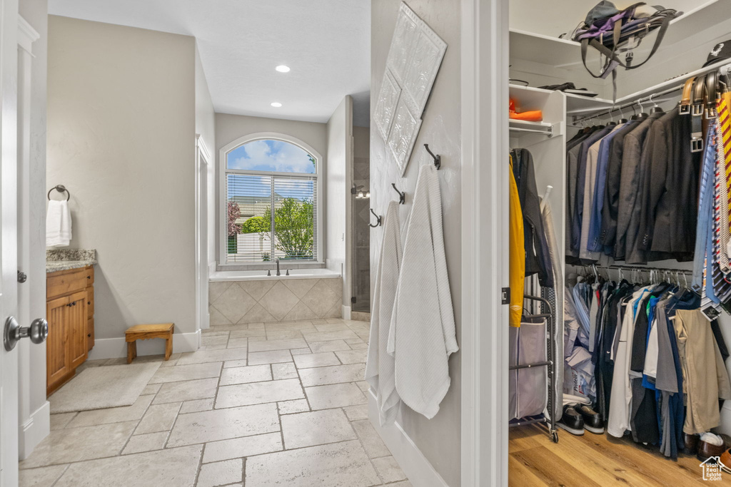 Bathroom featuring vanity, a garden tub, recessed lighting, baseboards, and a spacious closet
