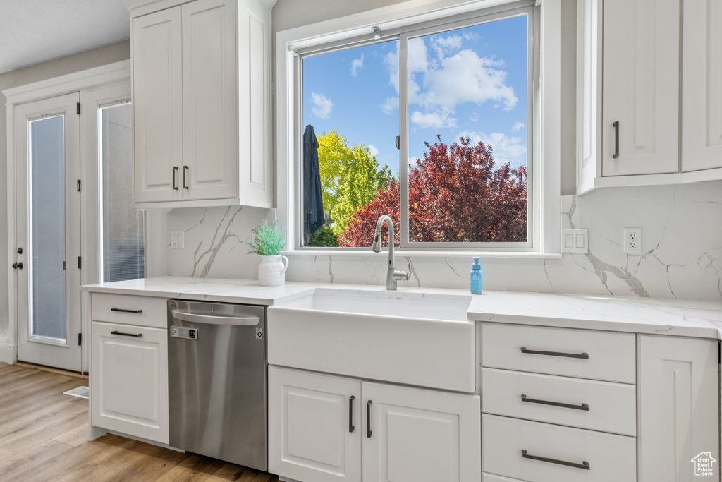 Kitchen with dishwasher, a sink, and white cabinets