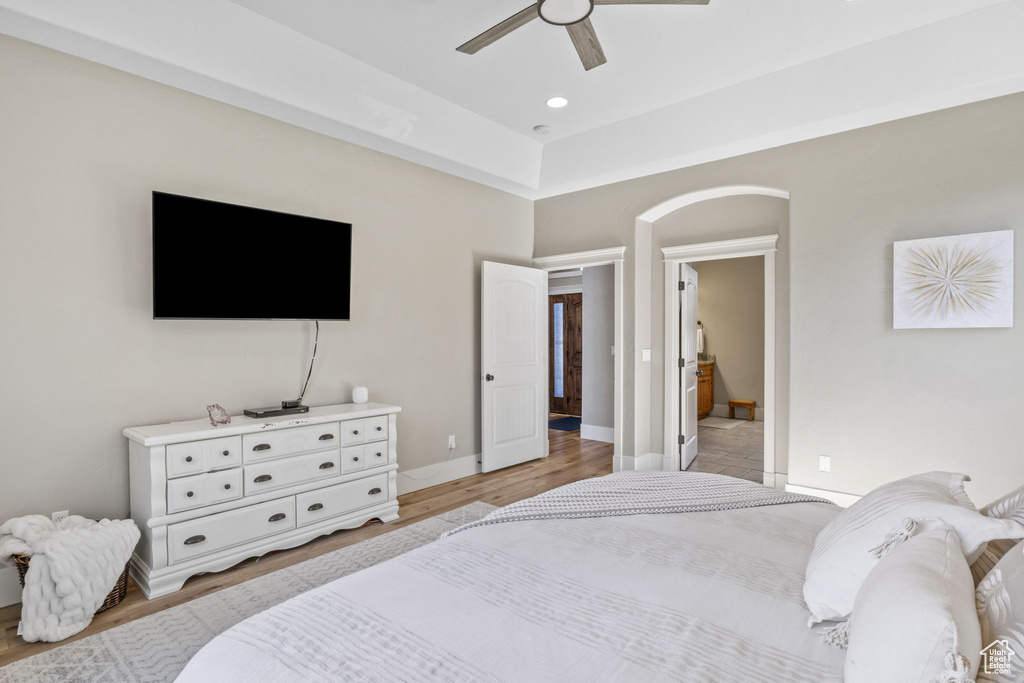 Bedroom with light wood-type flooring, a ceiling fan, baseboards, and arched walkways