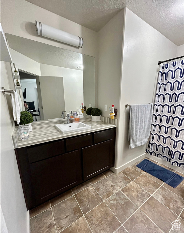Bathroom with a textured ceiling, vanity, and a shower with shower curtain