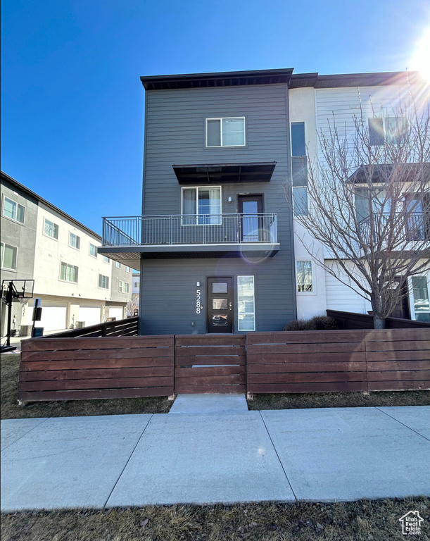 View of front of property with a balcony, a fenced front yard, and a gate