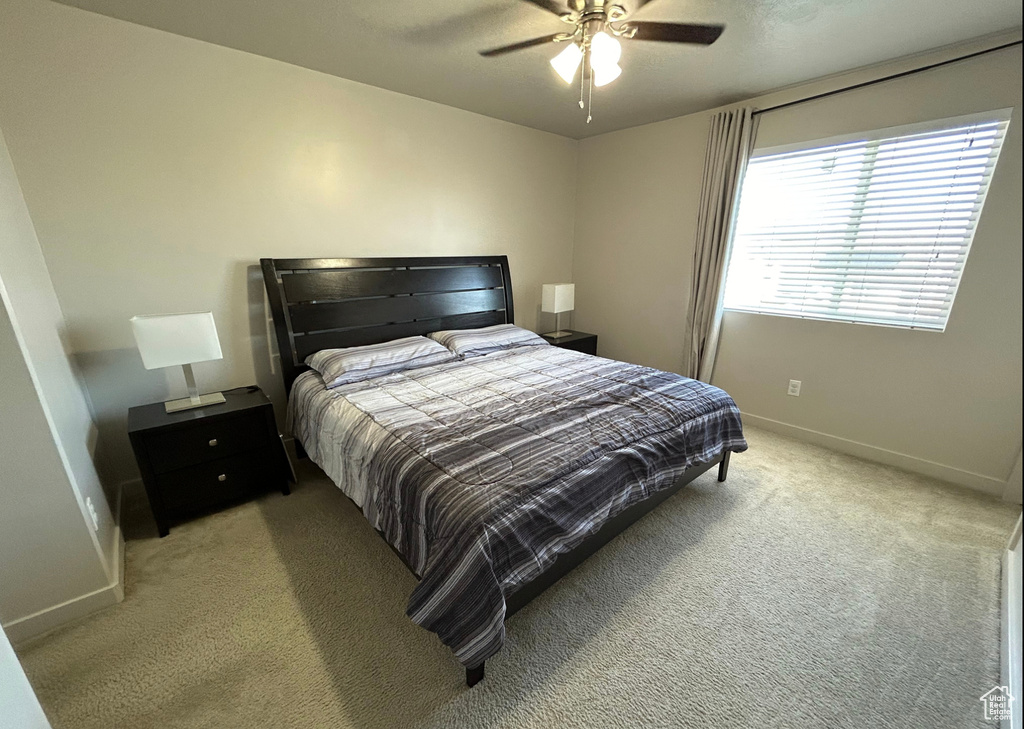 Bedroom with light colored carpet, baseboards, and a ceiling fan