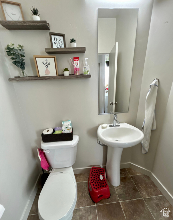 Bathroom featuring baseboards, toilet, and tile patterned flooring