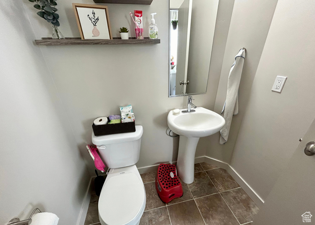 Bathroom featuring toilet, baseboards, and tile patterned floors