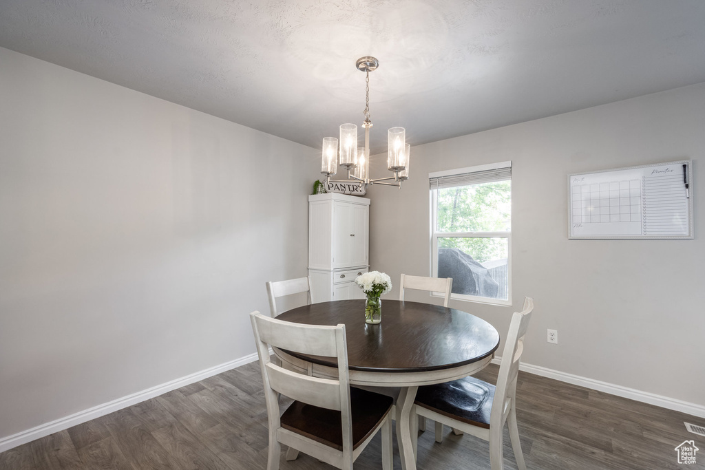 Dining space with dark wood-style floors, a chandelier, and baseboards