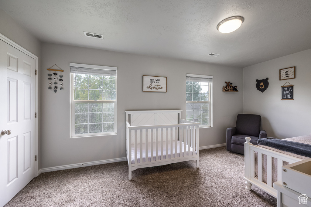 Carpeted bedroom with baseboards and a nursery area