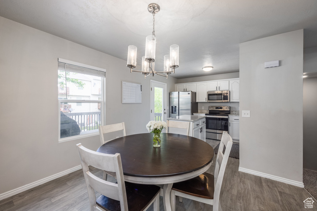Dining area with wood finished floors, a chandelier, baseboards, and healthy amount of natural light