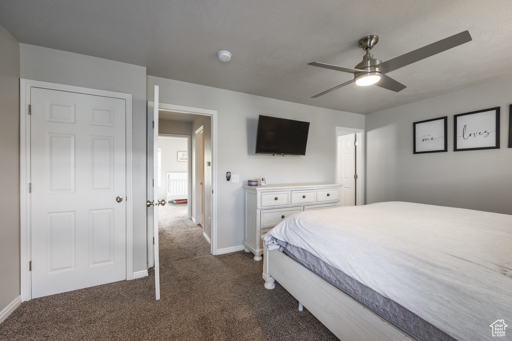 Bedroom with dark carpet, baseboards, and a ceiling fan