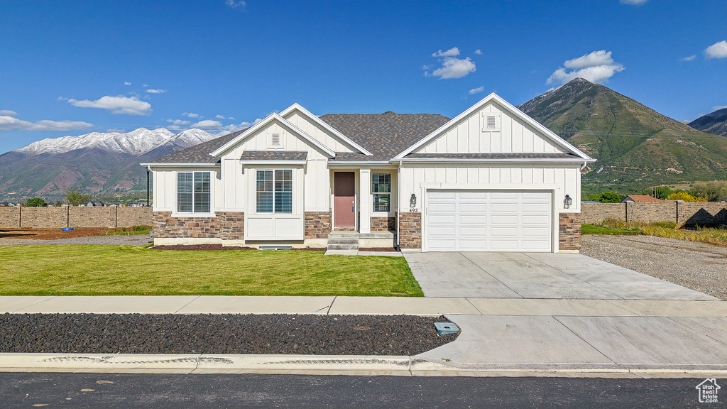 View of front of home featuring board and batten siding, stone siding, concrete driveway, and a mountain view