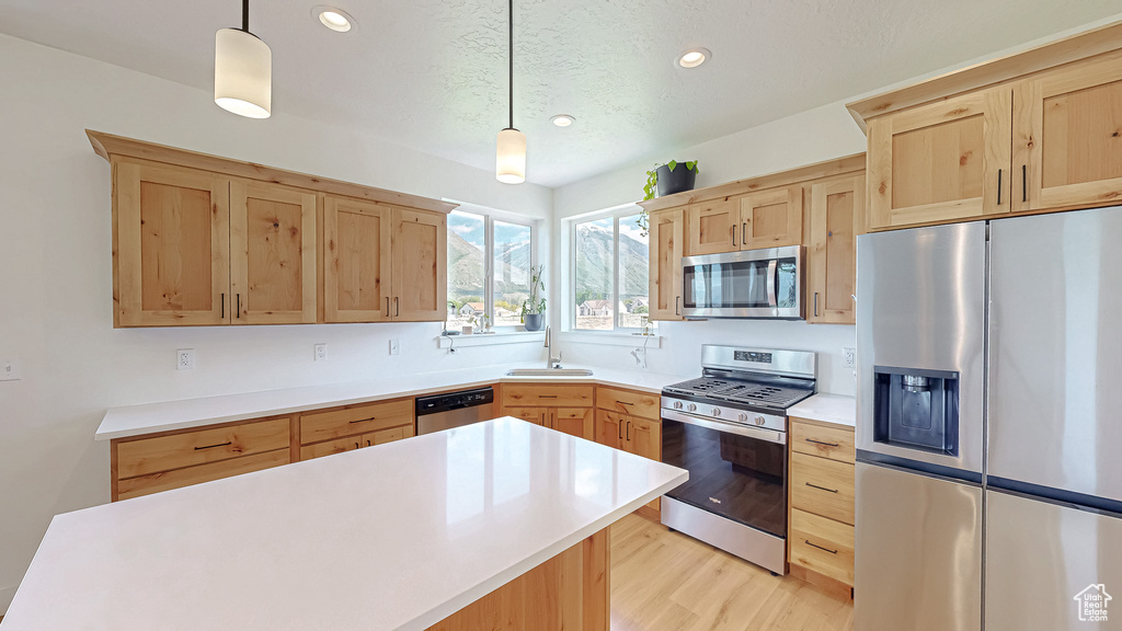 Kitchen with appliances with stainless steel finishes, light brown cabinetry, a sink, light countertops, and recessed lighting